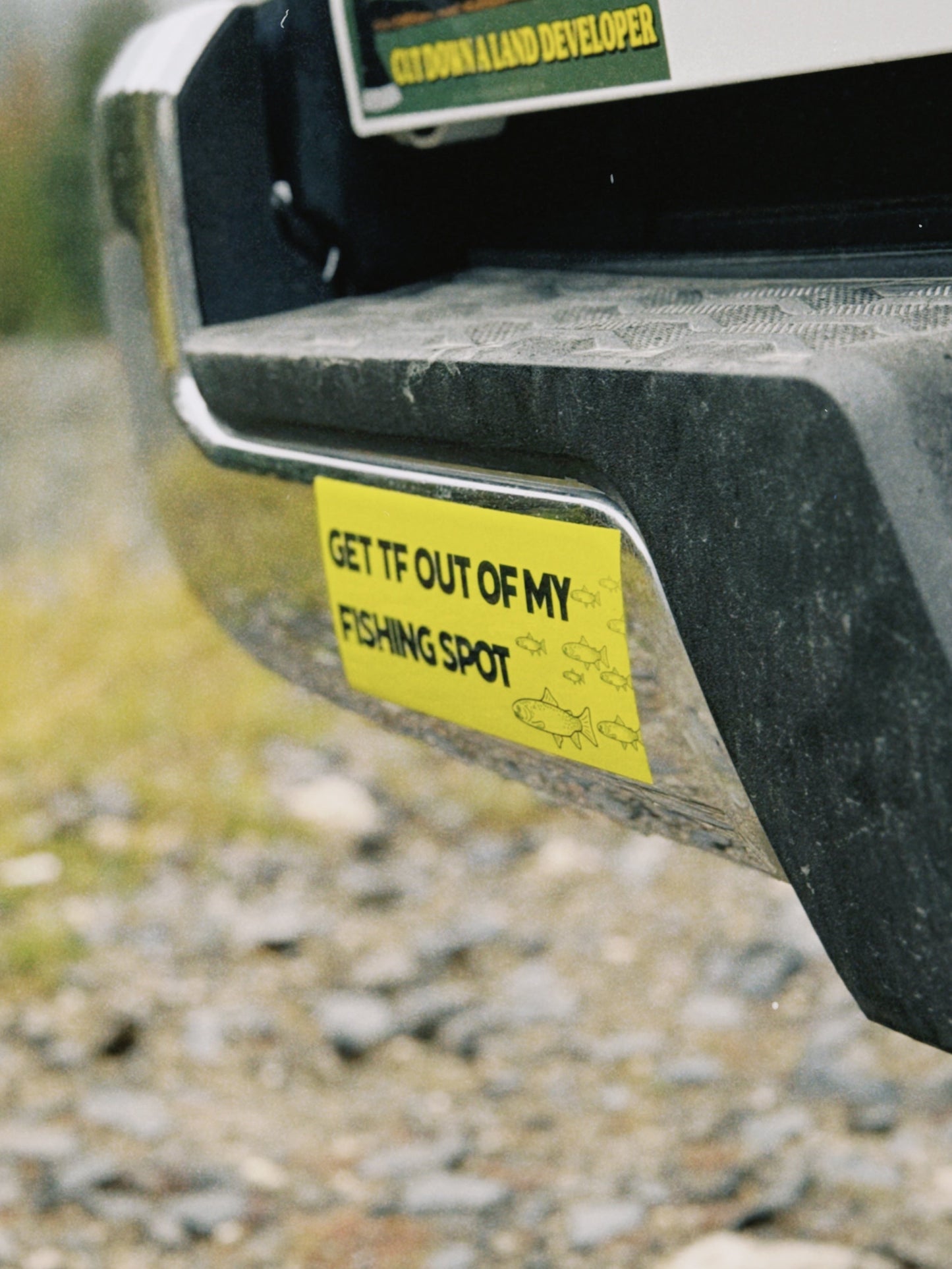 Bumper sticker on a vehicle's rear bumper with a natural background